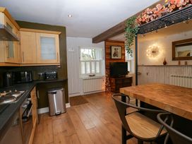 A kitchen and dining area with wooden cabinets and table a television and wall art at Flat 6 Aikbank in Whitehaven