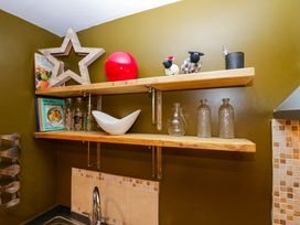 Wooden shelves above a kitchen sink with various decorative items and books at Flat 6 Aikbank in Whitehaven