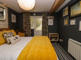 A bedroom with a bed covered with yellow bedding next to a door and patterned curtains at Flat 6 Aikbank in Whitehaven