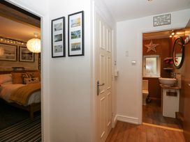 A hallway with framed pictures on the wall leading to a bedroom and a bathroom at Flat 6 Aikbank in Whitehaven