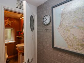 A hallway with a clock and a framed map on the wall next to an open door leading to a bathroom with a star decoration and a sink at Flat 6 Aikbank in Whitehaven
