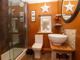 A bathroom with a shower enclosure a toilet a round sink on a wooden countertop and a small window at Flat 6 Aikbank in Whitehaven