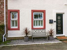 An exterior wall with two windows a bench two potted plants and a door at Flat 6 Aikbank in Whitehaven