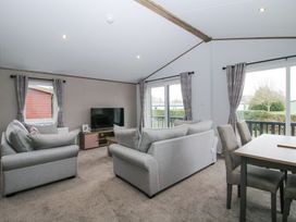 A living room with two sofas a television on a stand and a dining table with chairs at Peony in Eardisland