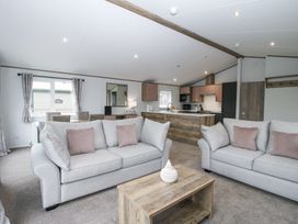 An open plan living room and kitchen with two sofas a wooden coffee table and dining area at Peony in Eardisland