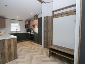 A kitchen area with cabinets appliances and a wooden bench with coat hooks at Peony in Eardisland