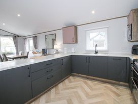 A kitchen with dark cabinets a white countertop and a window above the sink at Peony in Eardisland