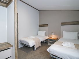 A bedroom with two single beds a nightstand and a lamp at Peony in Eardisland