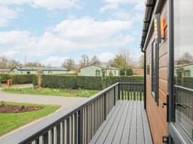 A balcony with railing outside a wooden building overlooking a road garden and other buildings at Peony in Eardisland