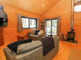 A living room with wooden walls and ceiling sofas wood burning stove and television at Forsa Lodge in Glenforsa near Salen Isle Of Mull
