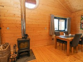 A dining area with a wooden table and chairs next to a wood burning stove in a room with wooden walls and floor at Forsa Lodge in Glenforsa near Salen Isle Of Mull