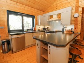 A kitchen with an island countertop stools a stove sink dishwasher and cabinets at Forsa Lodge in Glenforsa near Salen Isle Of Mull