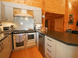 A kitchen with stove oven microwave toaster and refrigerator inside a wooden cabin at Forsa Lodge Glenforsa near Salen Isle Of Mull