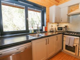 A kitchen with a sink under a window and appliances including a dishwasher microwave and oven at Forsa Lodge in Glenforsa near Salen Isle Of Mull