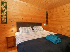 A bedroom with a double bed two pillows bedside table and wooden walls at Forsa Lodge Glenforsa near Salen Isle Of Mull