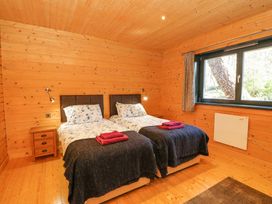 A bedroom with two single beds next to a wooden nightstand and a window at Forsa Lodge in Glenforsa near Salen Isle Of Mull