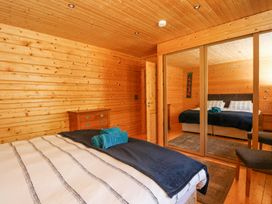 A bedroom with a bed with folded towels a wooden chest of drawers and mirrored sliding wardrobes at Forsa Lodge in Glenforsa near Salen Isle Of Mull