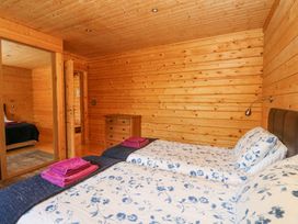 A bedroom with two beds blue floral bedding wooden walls and a chest of drawers at Forsa Lodge in Glenforsa near Salen Isle Of Mull