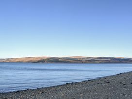 A rocky shoreline with water and hills in the background at Forsa Lodge Glenforsa near Salen Isle Of Mull
