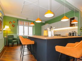 A kitchen with green walls orange pendant lights and bar stools at Sycamore Apartment in Lifton