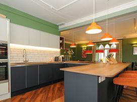 A kitchen with an island and orange pendant lights a wooden countertop and green walls at Sycamore Apartment in Lifton