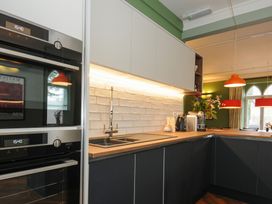 A kitchen with black and white cabinets a wooden countertop built in ovens a sink and pendant lights at Sycamore Apartment in Lifton