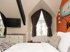 A bedroom with a bed next to a window with dark curtains and a dresser with a television above at Sycamore Apartment in Lifton