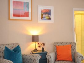 Two armchairs with cushions and a side table with a lamp and flowers in a room at Sycamore Apartment in Lifton