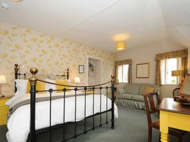 A bedroom with a black and brass bed a yellow desk green sofa and two windows at Sycamore Apartment in Lifton