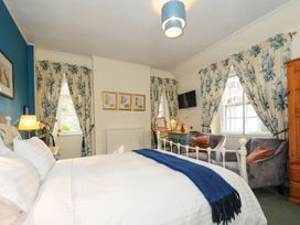 A bedroom with a bed a desk two armchairs floral curtains and a wall mounted television at Sycamore Apartment in Lifton