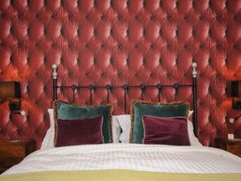 A bed with green and purple pillows against a red tufted wall at Sycamore Apartment in Lifton