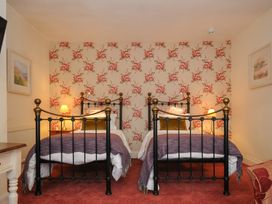 A bedroom with two single metal beds and floral wallpaper at Sycamore Apartment in Lifton