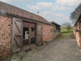 An outdoor area with stone buildings wooden doors and a gravel path at The Barn in Spaxton