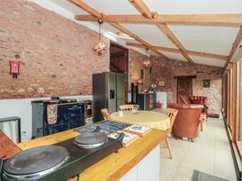 A kitchen and sitting area with stone walls wooden beams and large windows at The Barn in Spaxton