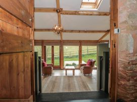 A sitting area with two armchairs and a small table by large glass doors overlooking a grassy field at The Barn in Spaxton