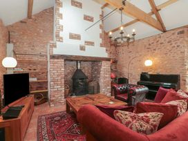 A living room with a red sofa and armchair a fireplace a piano and a television at The Barn in Spaxton