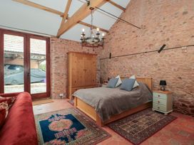 A bedroom with a wooden bed sofa wooden wardrobe and stone walls at The Barn in Spaxton