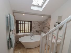 A bathroom with a freestanding bathtub under a window a skylight a sink and a towel rail at The Barn in Spaxton