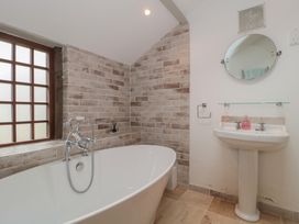 A bathroom with a freestanding bathtub a sink with mirror and tiled walls at The Barn in Spaxton