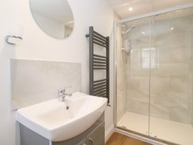 A bathroom with a sink, mirror, and shower at 23 Carncrows Street, St Ives