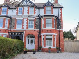 A red brick and white window house with potted plants and an arched doorway at Dolawen Bach in Conwy