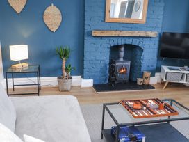 A living room with a blue brick fireplace wood stove plant and a game board on the table at Dolawen Bach in Conwy