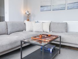 A living room with a grey corner sofa pillows on sofa and a glass coffee table with a board game at Dolawen Bach in Conwy