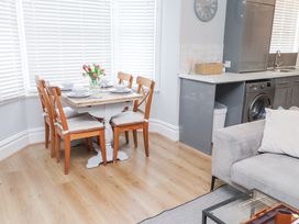 A dining area with a table set with dishes and flowers near a kitchen with gray cabinets and a washing machine at Dolawen Bach in Conwy