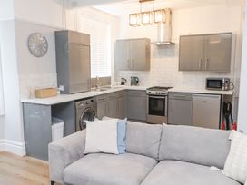 A kitchen with grey cabinets stainless steel appliances and a grey sofa in front at Dolawen Bach in Conwy