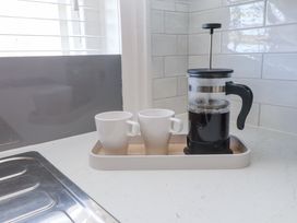 A kitchen countertop with a tray holding a coffee press and two white mugs at Dolawen Bach in Conwy