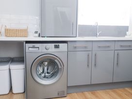 A laundry area with a washing machine sink and storage bins at Dolawen Bach in Conwy