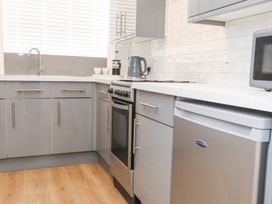 A kitchen with grey cabinets a countertop a sink a stove a kettle a microwave and a small refrigerator at Dolawen Bach in Conwy