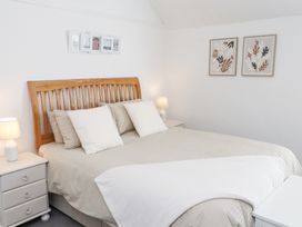 A bedroom with a wooden bed frame two bedside tables with lamps and framed artwork on the walls at Dolawen Bach in Conwy
