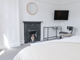A bedroom with a bed a black fireplace a round mirror a metal desk a chair and a wall-mounted TV at Dolawen Bach in Conwy